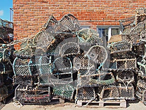 lobster pots used in traditional fishing for crustaceans stacked against a building in scarborough harbour