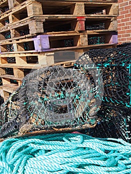 lobster pots used in traditional fishing for crustaceans stacked together on top of green nylon rope and pallets in scarborough