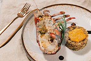 Lobster with risotto on a white plate with fork and knife.