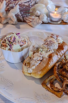 Lobster salad in a fresh brioche roll with homemade fried onion rings and coleslaw