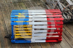 A lobster trap with the Acadian flag painted on it.