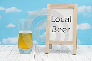 Local Bear sign with cold glass of beer with whiteboard on weathered wood