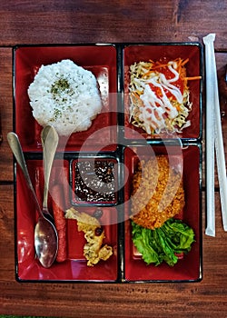 A Local Bento bowl, rice with chicken katsu, extra vegetable salad and sausage sauce.