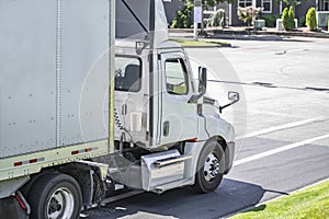 Local carrier day cab big rig semi truck with dry van semi trailer running on the city street for delivery