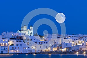 Local church of Naoussa village at Paros island in Greece against the full moon.