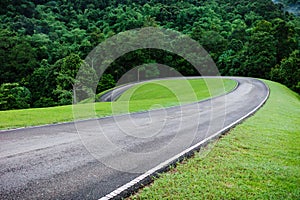 Local curved road on hill slope inside tropical rainforest