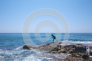A local fisher man casting his fishing rod on rocks sea coast, shore of the Bay in Asia, Thailand