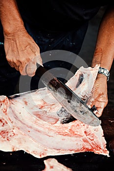 Local fisherman cleaning a manta ray at the fishing market next to the shore