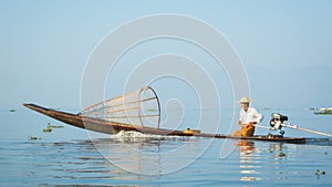 Local fisherman floats on fishing boat with a motor. Inle lake, Burma (Myanmar)