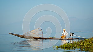 Local fisherman is moving quickly on the boat with a modern engine. Inle Lake, Myanmar