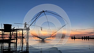 Local fisherman with scoop the fish out of the giant yoke