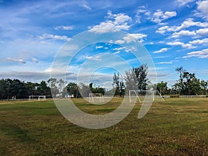 Local football stadium with goal post and blue sky and white clouds background in the rural area. Soccer field in the provincial