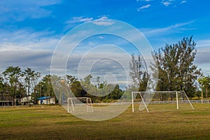 Local football stadium with goal post and blue sky and white clouds background in the rural area. Soccer field in the provincial