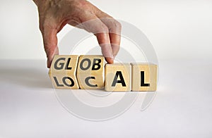 Local or global symbol. Businessman turns wooden cubes and changes the word `local` to `global`. Beautiful white table, white