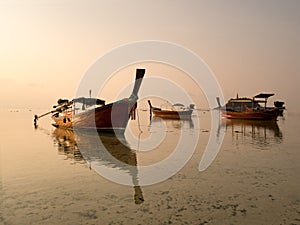 Local long tail boat in sea at sunrise when tide is falling or going out. Peaceful feeling at Lipe Island, Satun, Thailand