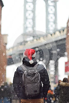 Local man in a Santa Claus hat is walking during a snowfall near Manhattan Bridge in New York on a snowy Christmas Eve. Winter