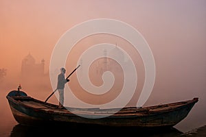 Local man standing in a boat on Yamuna River near Taj Mahal in early morning, Agra, Uttar Pradesh, India