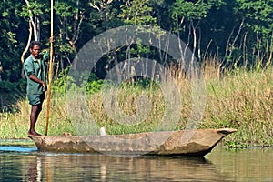 Local man traveling by rowboat at wild river in Chitwan National Park, Nepal