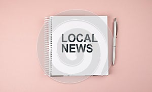 LOCAL NEWS text on notebook with pen on the pink background