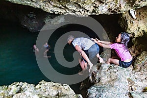 Local Polynesian teens swimming in Veimumuni cave, while a small girl shoves a boy to the pool. Motion blur. Vavau, Tonga.