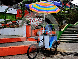 Local small shop on a bike selling drink under a bright and colorful umbrella in south america