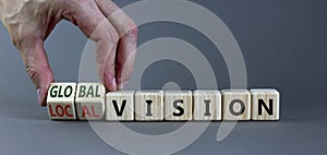 From local to global vision. Businessman turns cubes and changes words `local vision` to `global vision`. Beautiful grey
