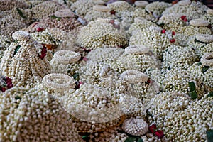 Local traditional Thai style flower offering on temple floor including pile of jasmine garlands made of white jasmine
