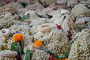 Local traditional Thai style flower offering on temple floor including pile of jasmine garlands made of white jasmine