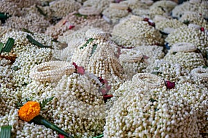 Local traditional Thai style flower offering on temple ground including pile of jasmine garlands made of white jasmine