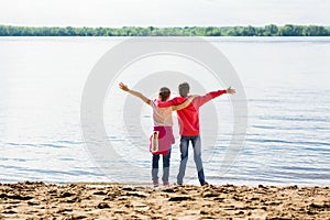 Local travel. Two girls hug on the river bank in the sand with arms outstretched. Summer tourism