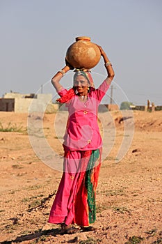 Local woman carrying jar with water on her head, Khichan village