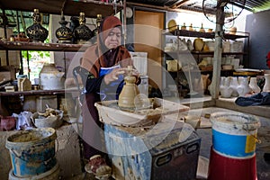 Local woman demonstrates on making traditional clay jar called