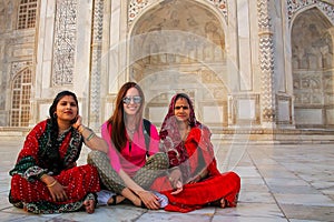 Local women and a foreign girl sitting outside Taj Mahal in Agra