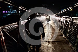 Locals crossing bridge at night photo