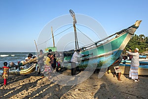 Locals help push an outrigger canoe back onto the beach at Arugam Bay in the late afternoon.