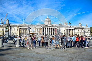 Locals and tourists gathering and hanging out at Trafalgar Square in front of National Gallery in London, England, UK