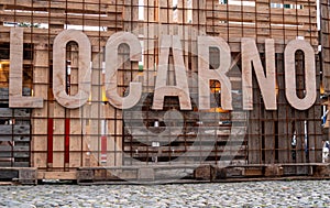 Enormous wooden letters introducing town Locarno, fasten on wooden plank fence around the skating ring on the square