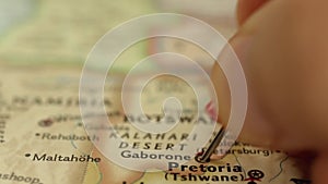 Location Gaborone in Botswana, Africa on travel map, man hand push pin close-up