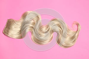 Lock of blonde wavy hair on color background