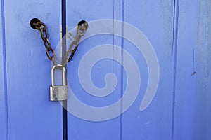 Lock on a blue door with a chain on the right there is a place for an