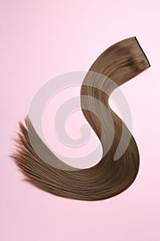 Lock of brown straight hair on color background