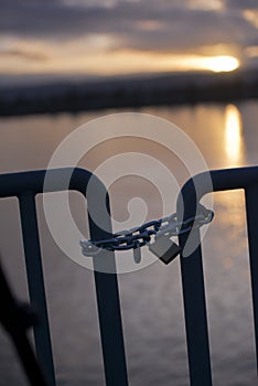 Lock on chain on barrage turnstile evening river sunset