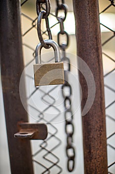 Lock on a chain link security fence. Chicken wire fence gate is locked with a chain and a padlock