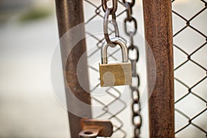 Lock on a chain link security fence. Chicken wire fence gate is locked with a chain and a padlock