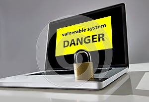 Lock on computer laptop keayboard with warning message danger vulnerable system in hacker attack concept photo