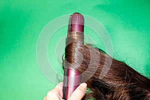 A lock of dark hair is wrapped around a hot Styler