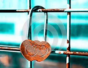 Lock made of rusty hearts fixed on a grid. Teal and orange filter