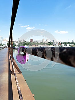 Lock on the railing of the bridge over the river. In the far visible city. Love. Faithfulness. Marriage