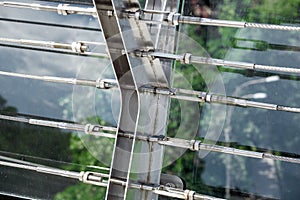 Lock sling steel and screw a close up view of detail of clamps system on glass bridge.