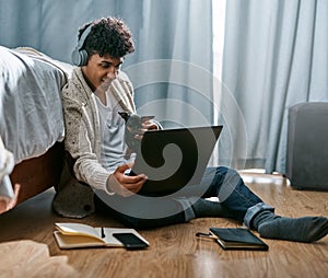 Lockdown...everyday is bring your dog to work day. a young man using a laptop and headphones with his dog while working